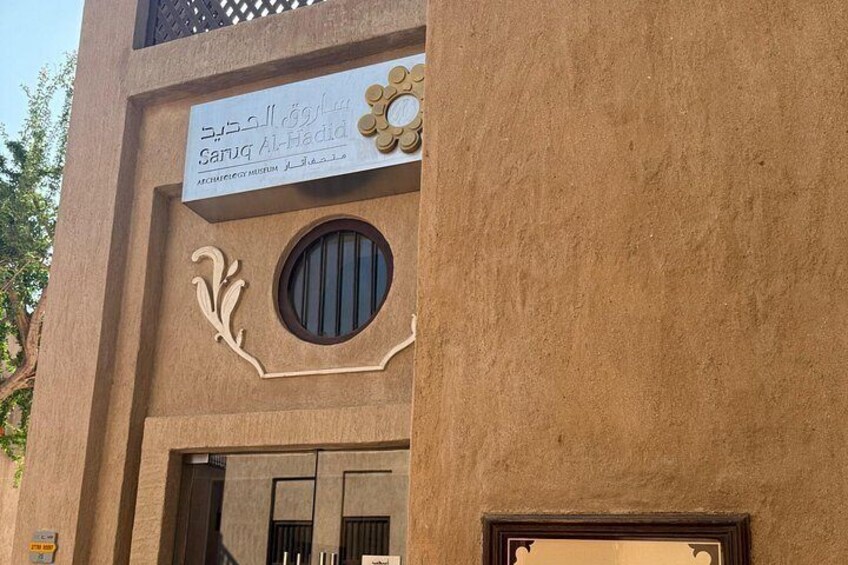 Un edificio con un letrero que dice 'Sanuq Al-Hadid' y un ventanal circular decorativo. 2