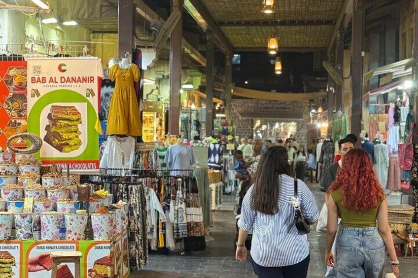 Un marché animé où l’on trouve de nombreux étals vendant des chocolats et des vêtements. 3