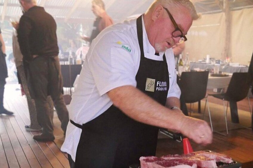 A person in a white shirt and black apron preparing food at a table. 2