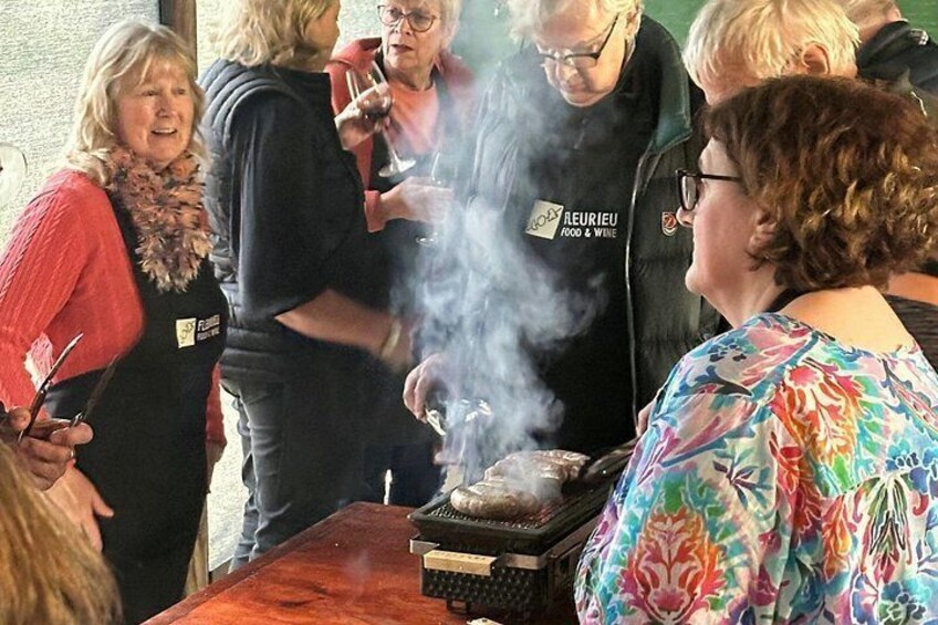 A group of people around a barbecue grill with food being cooked. 5