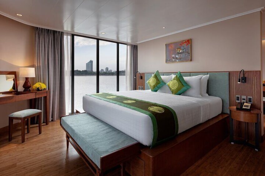 A hotel room with a large bed, a desk, a chair, and a view of the water. 4