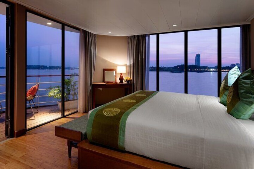 A bedroom with a large bed, a view of the water, and a chair by the window. 2