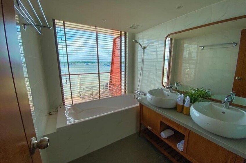 A bathroom with a bathtub, two sinks, a large mirror, and a window with blinds. 5