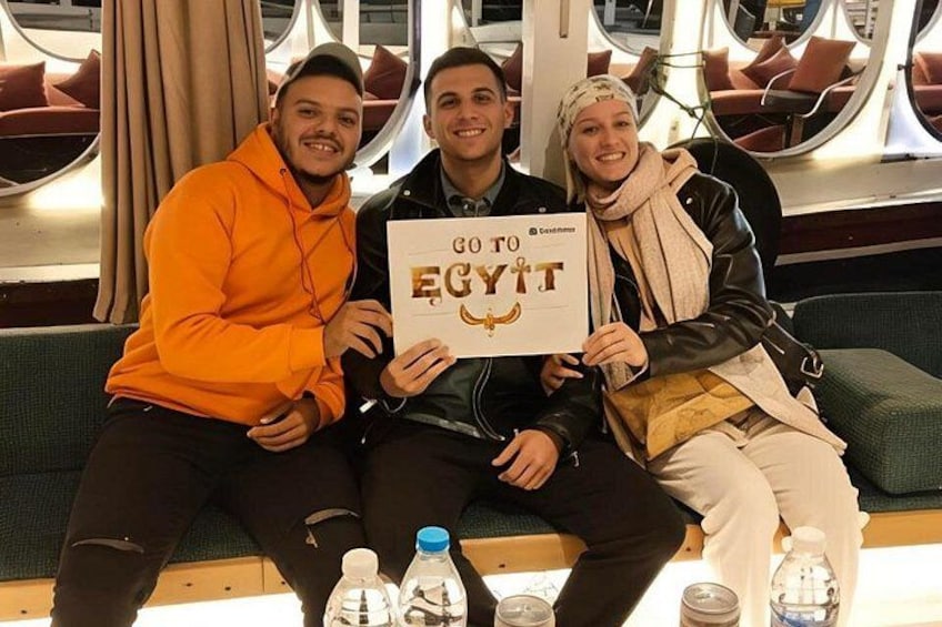 Tre persone sedute su una panchina con un cartello che recita 'GO TO EGYPT'. 1