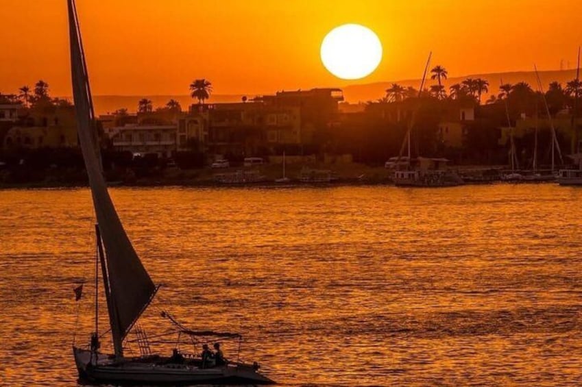 Un velero en aguas tranquilas durante el atardecer, con un paisaje urbano al fondo. 5