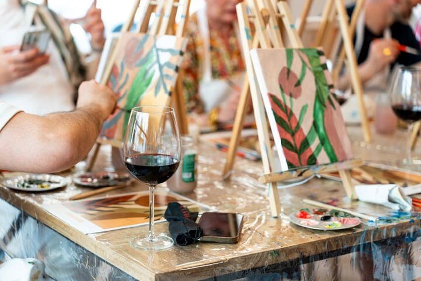 An art class with easels, paint palettes, and wine glasses. 2