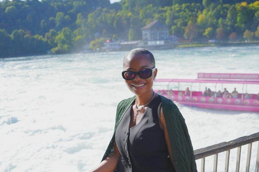 A person standing by a river with a boat in the background. 2