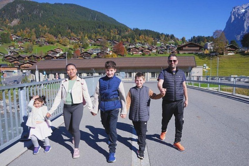 A family walking on a bridge with a mountainous landscape in the background. 4