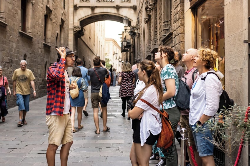 Un grupo de personas en una calle adoquinada, mirando hacia arriba un arco. 2