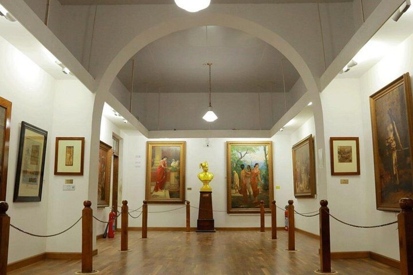 An art gallery with wooden flooring, white walls, and paintings displayed on the walls. 5