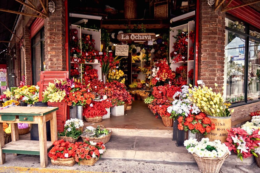 A flower shop named La Ochava with a variety of colorful flowers displayed outside. 4