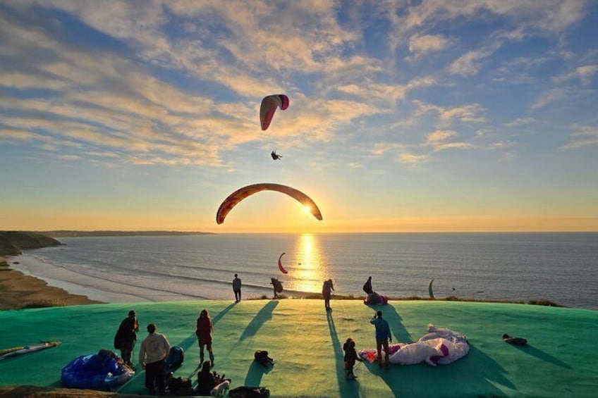 A beach with people engaging in paragliding activities. 2