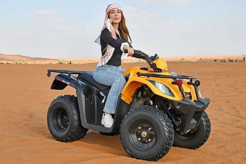 Iemand rijdt op een gele quad door een woestijn. 1