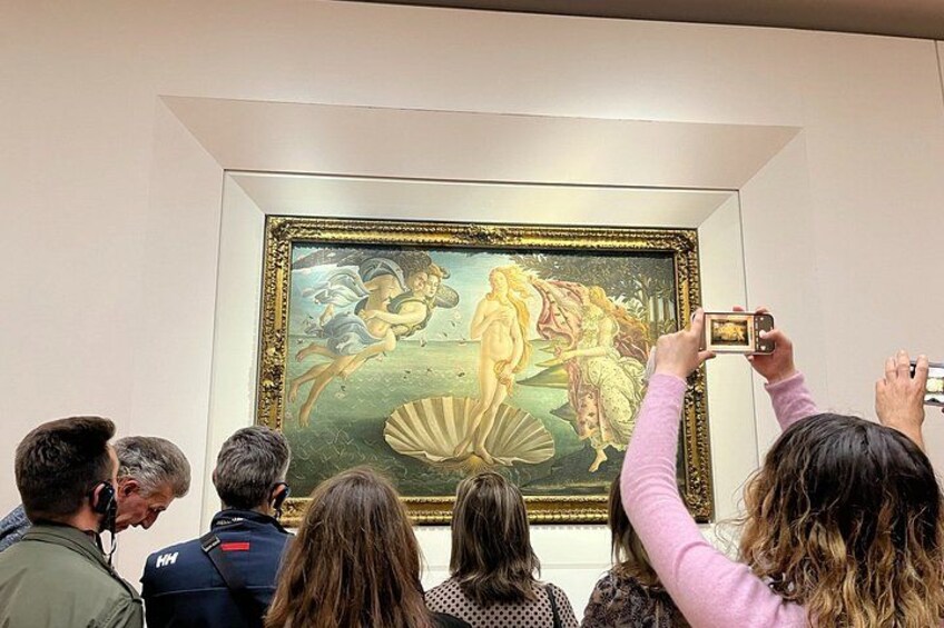 Un grupo de personas observando un cuadro enmarcado en un museo. 1