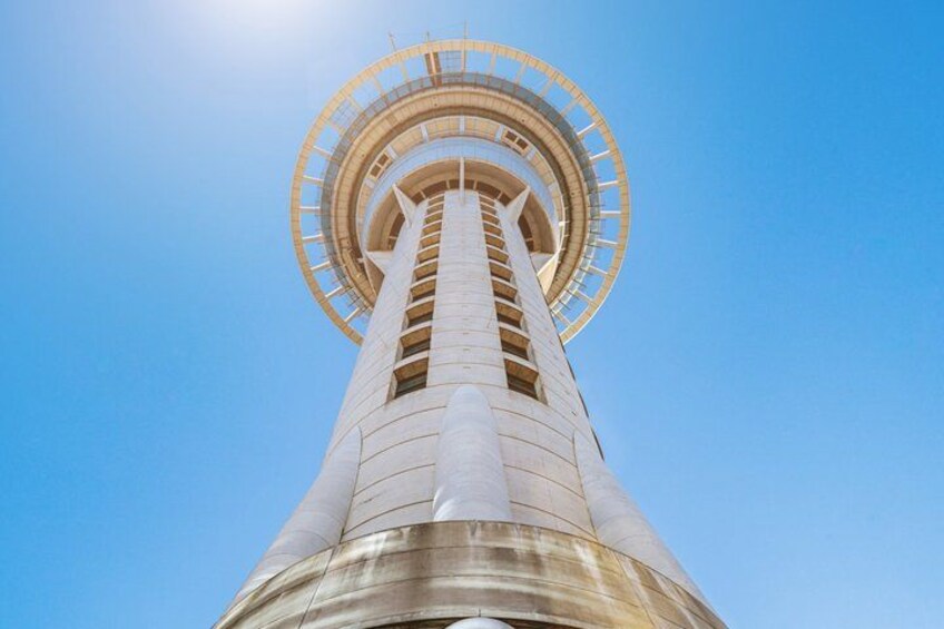 A tall tower with a circular observation deck at the top against a clear blue sky. 2
