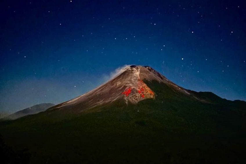 A mountain at night with a red glow on its peak. 4