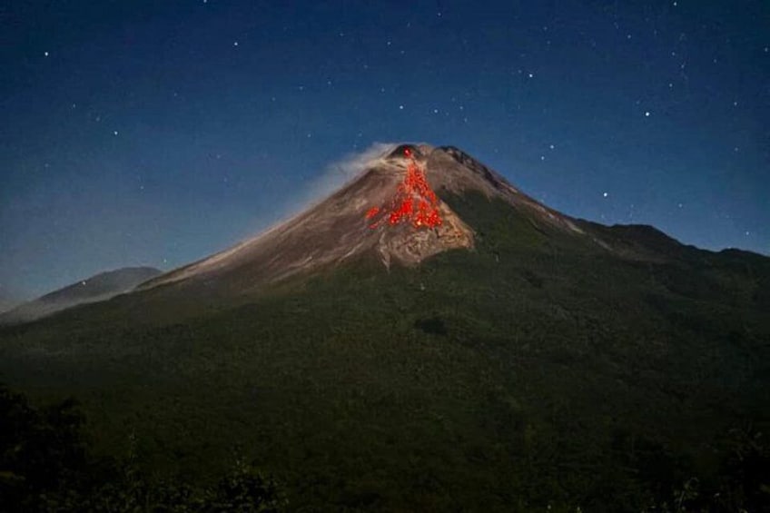 A mountain with a glowing red volcanic crater at night. 3