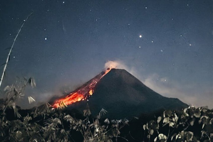 Un volcán en erupción nocturna, con visible flujo de lava. 1