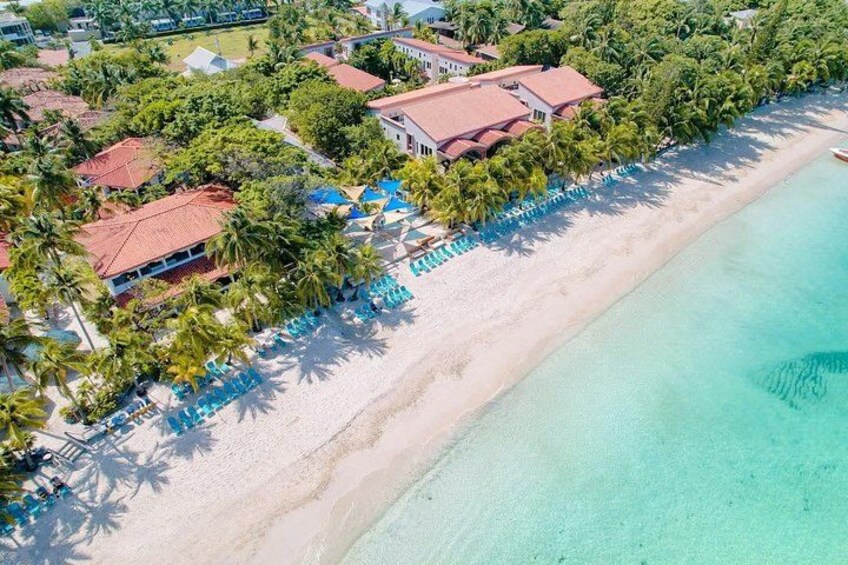 A beach with clear turquoise water, a sandy shore, and a row of blue lounge chairs. 3