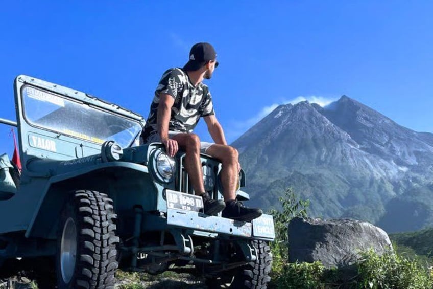 A person sitting on a vehicle with a mountain in the background. 1