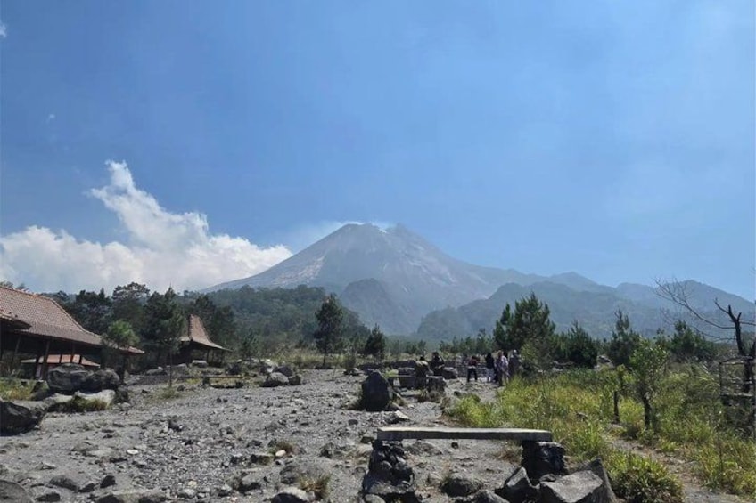 A mountainous landscape with a volcano, traditional buildings, and a rocky path. 2