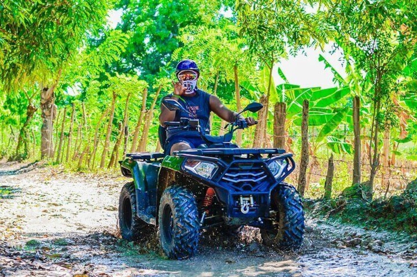 A person riding a quad bike on a dirt path surrounded by trees. 2