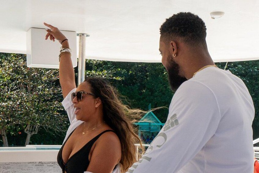 A person pointing at a structure, with a boat and greenery in the background. 4