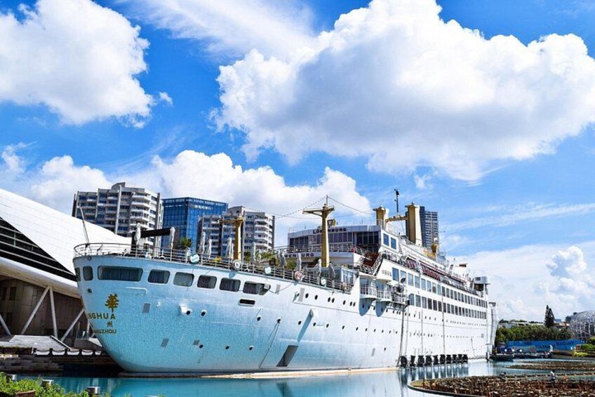 Een groot cruiseschip ligt aangemeerd in een haven, met moderne gebouwen op de achtergrond. 5
