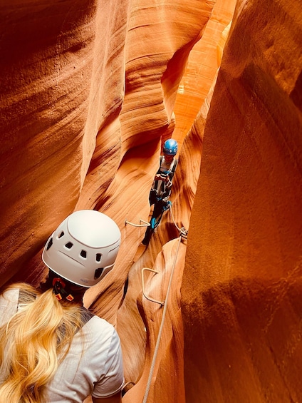 A person rappelling down a canyon with a helmet and harness. 4