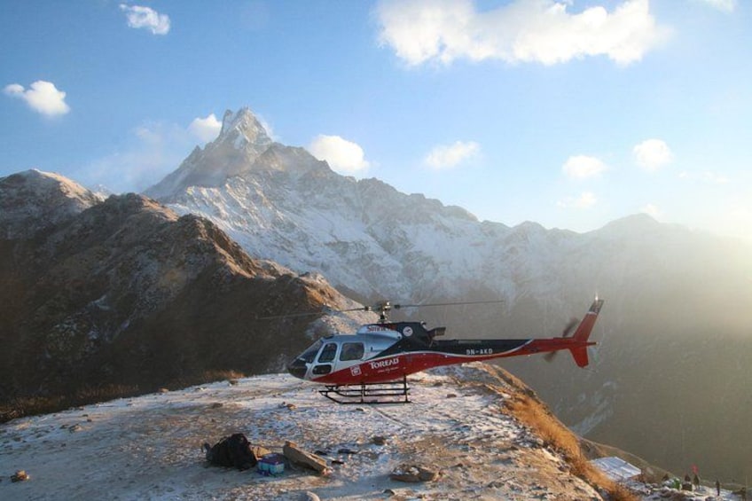 En rød og hvid helikopter på et snøklædt bjerg med en klar himmel. 1