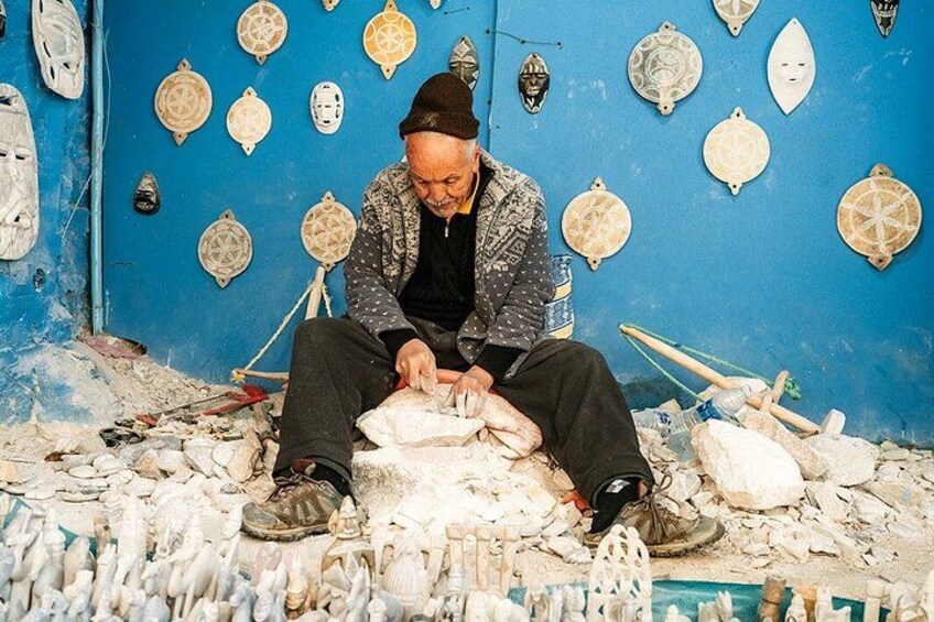 A person working with pottery on the floor, surrounded by various pottery items and tools. 2