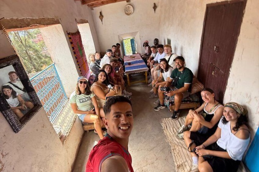 A group of people sitting in a rustic room with a wooden door and a patterned wall. 3