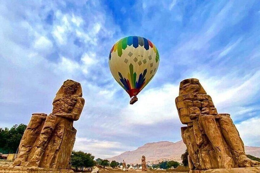 Un globo aerostático entre dos grandes formaciones rocosas, con un paisaje montañoso al fondo. 2