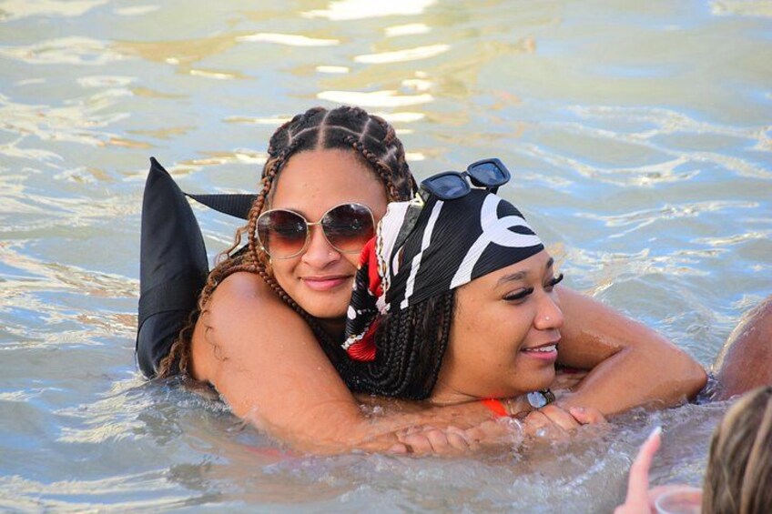 Two people in a body of water, wearing swimwear and accessories. 3