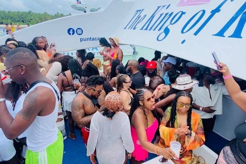 A crowded event on a boat with a banner reading 'The King of.' 2