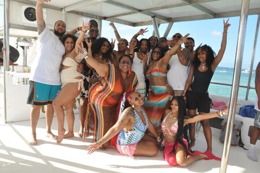 A group of people on a boat, some standing, some sitting, with the ocean in the background. 4