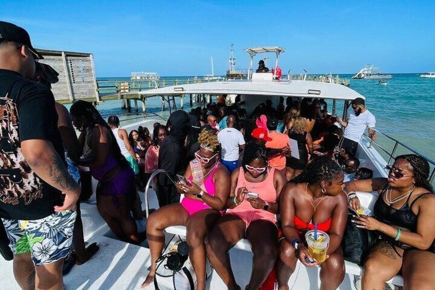 A boat with people on deck, a pier in the background, and calm water. 2