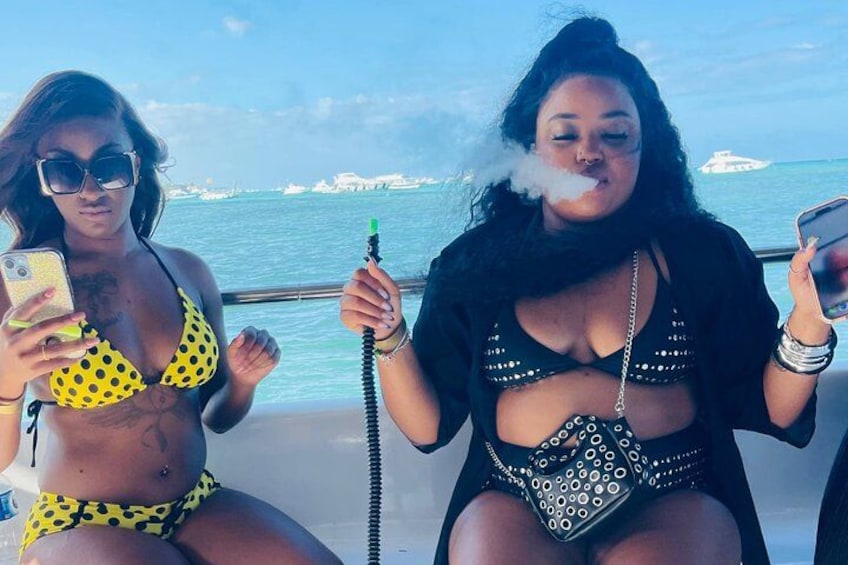 Two people on a boat, one holding a phone and the other holding a hookah. 5