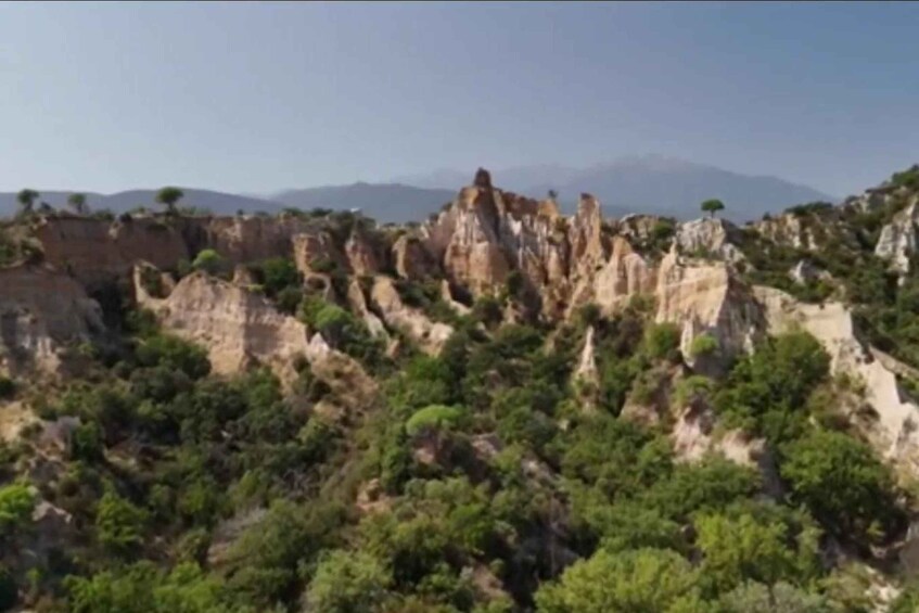 A rocky landscape with prominent limestone formations and dense green vegetation. 2