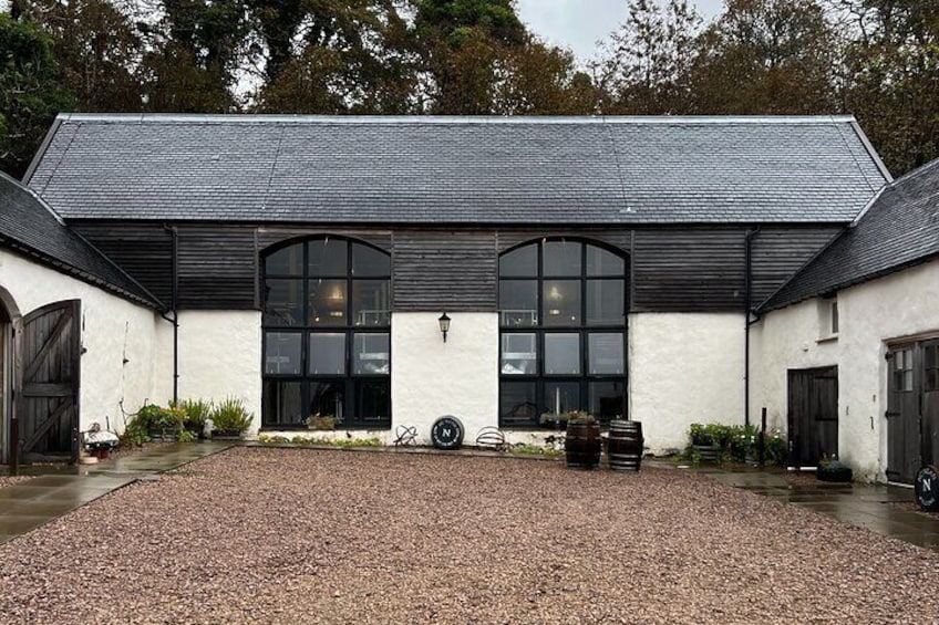 A white building with black trim, large arched windows, and a gravel driveway. 3