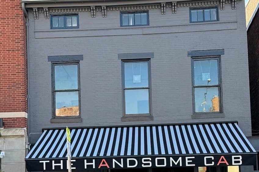 A building with a sign that reads 'THE HANDSOME CAB'. 4