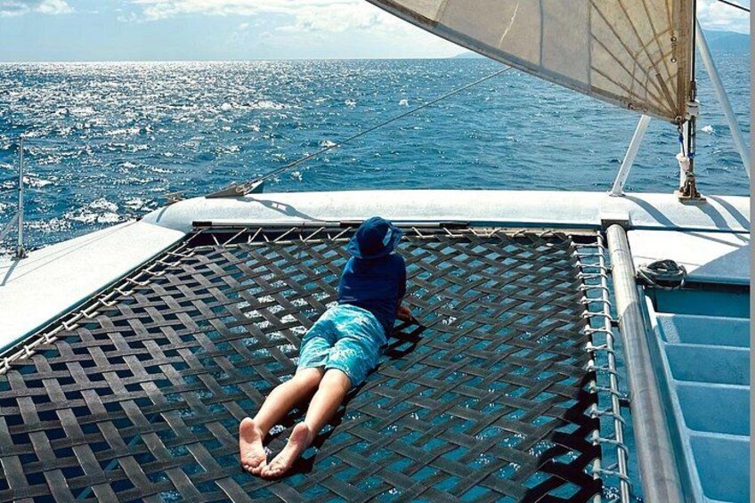 A person lying on a boat's deck, facing the ocean. 4