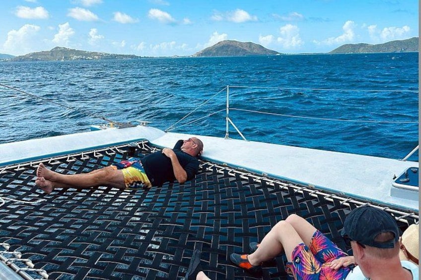 A person lying on a boat deck with a view of the ocean and distant land. 5