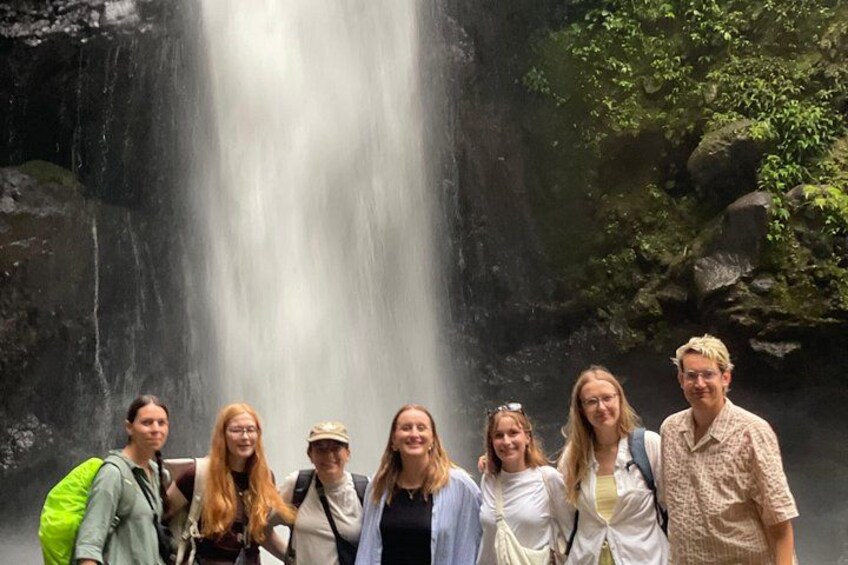 Een groep mensen staat voor een waterval. 2