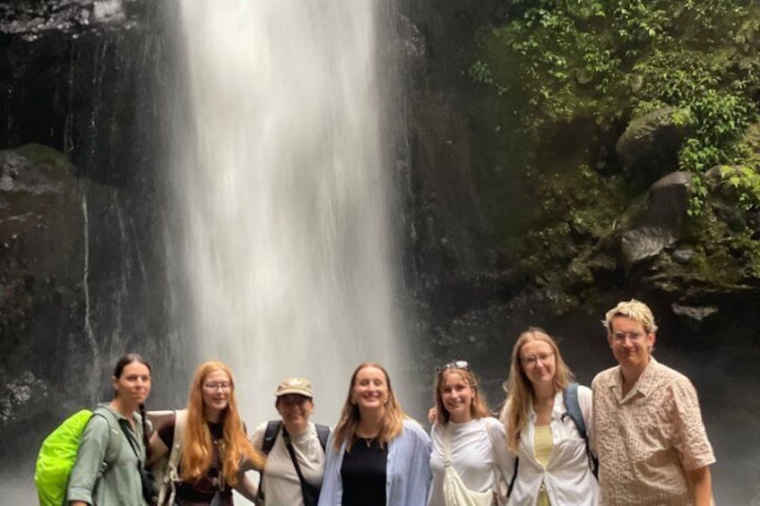 A group of people standing in front of a waterfall. 3
