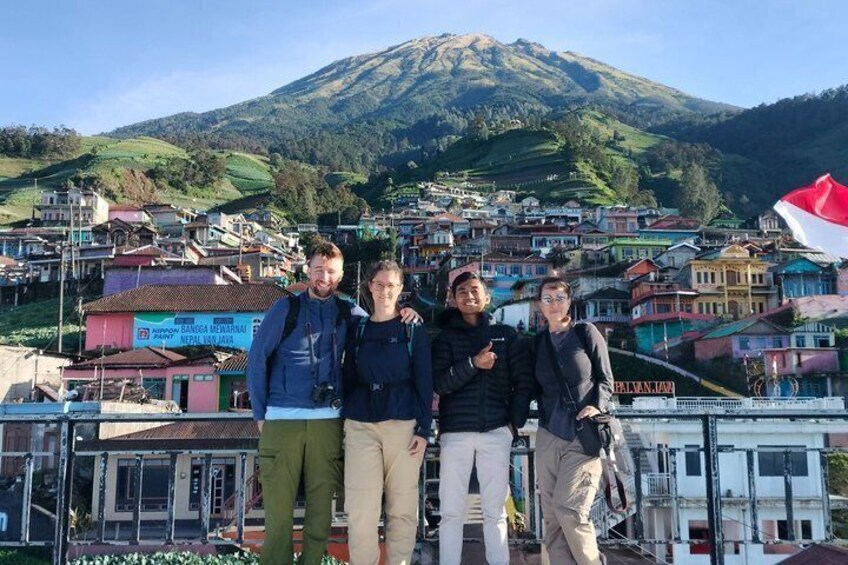 A group of people standing in front of a colorful town with a mountain in the background. 1