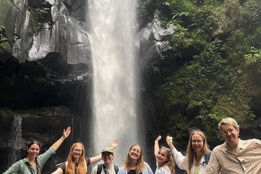 A group of people standing in front of a waterfall. 2