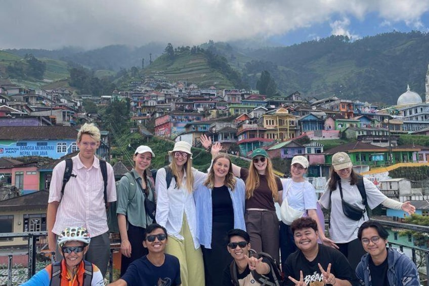 A group of people standing on a rooftop with a view of colorful buildings and a dome in the distance. 5