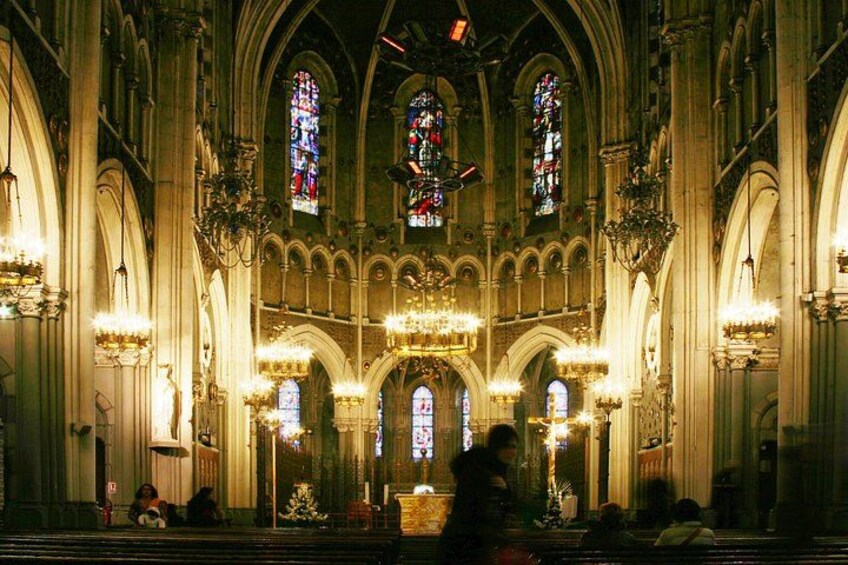 Interno di una cattedrale con soffitti a volta alti, vetrate colorate e numerosi lampadari. 4