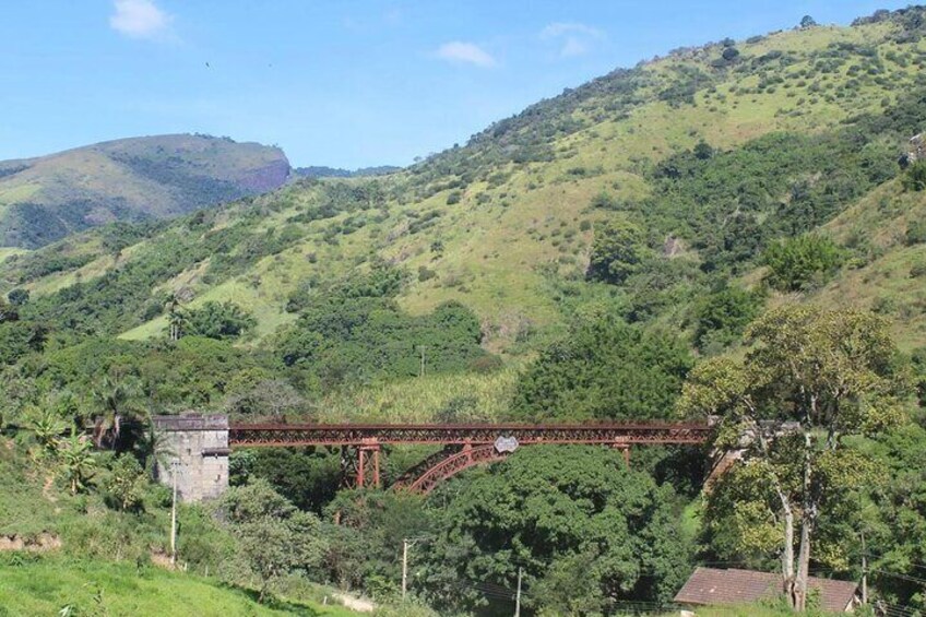 A red bridge over a river in a hilly, green landscape. 3